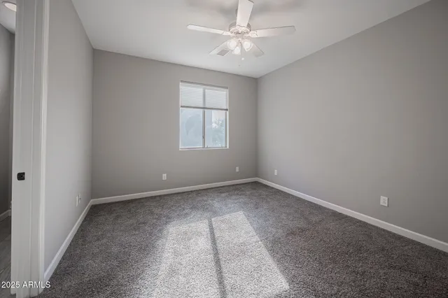 an empty room with chandelier fan and windows