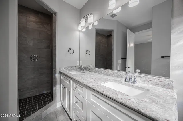 a bathroom with a granite countertop sink a shower and a mirror
