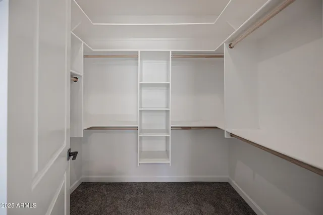 an empty room with chandelier fan and windows