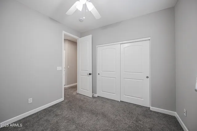 an empty room with closet and a chandelier fan