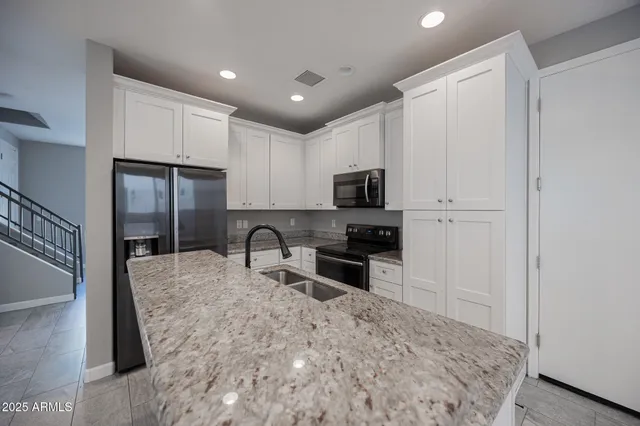 a kitchen with granite countertop a stove a sink and a refrigerator