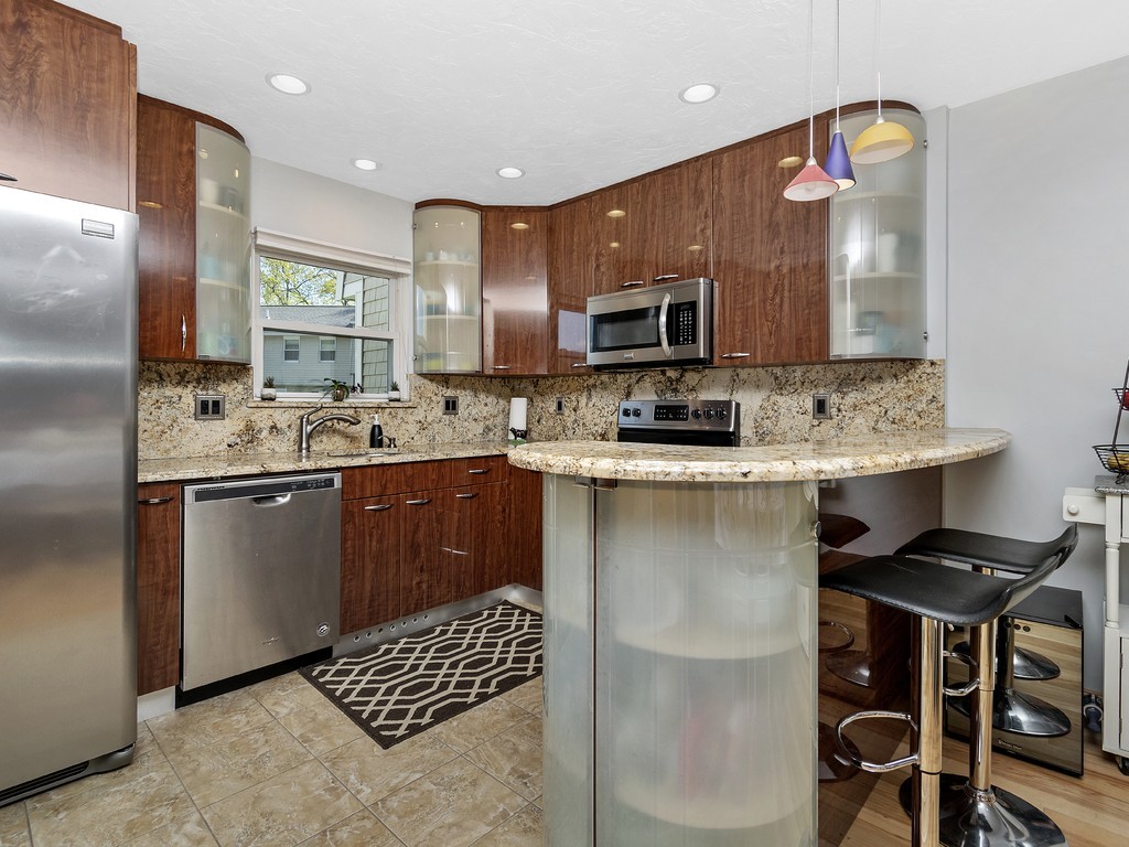 2255 Commonwealth Avenue, Unit 2255 Newton, MA 02466 - Photo 5 of 32 a kitchen with stainless steel appliances kitchen island granite countertop a sink a stove a refrigerator cabinets and chairs