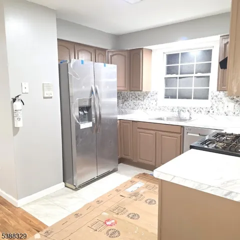 a kitchen with stainless steel appliances kitchen island granite countertop a refrigerator and a sink