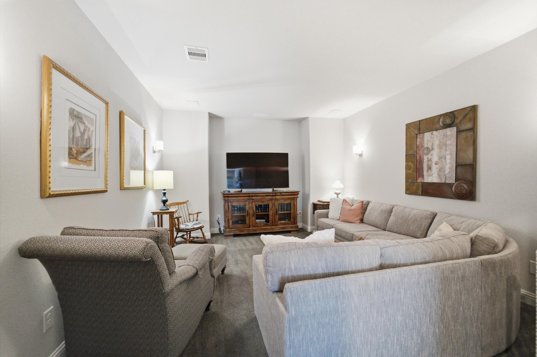 23722 Thortons Park Lane Spring, TX 77389 - Photo 35 of 48 This cozy living room features a large sectional sofa, a comfortable armchair, and a modern TV unit. Soft lighting and tasteful artwork create a welcoming atmosphere, perfect for relaxation and entertainment.