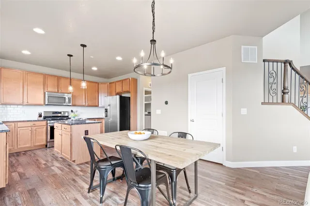 a kitchen with stainless steel appliances granite countertop a refrigerator a sink a stove and a wooden floor