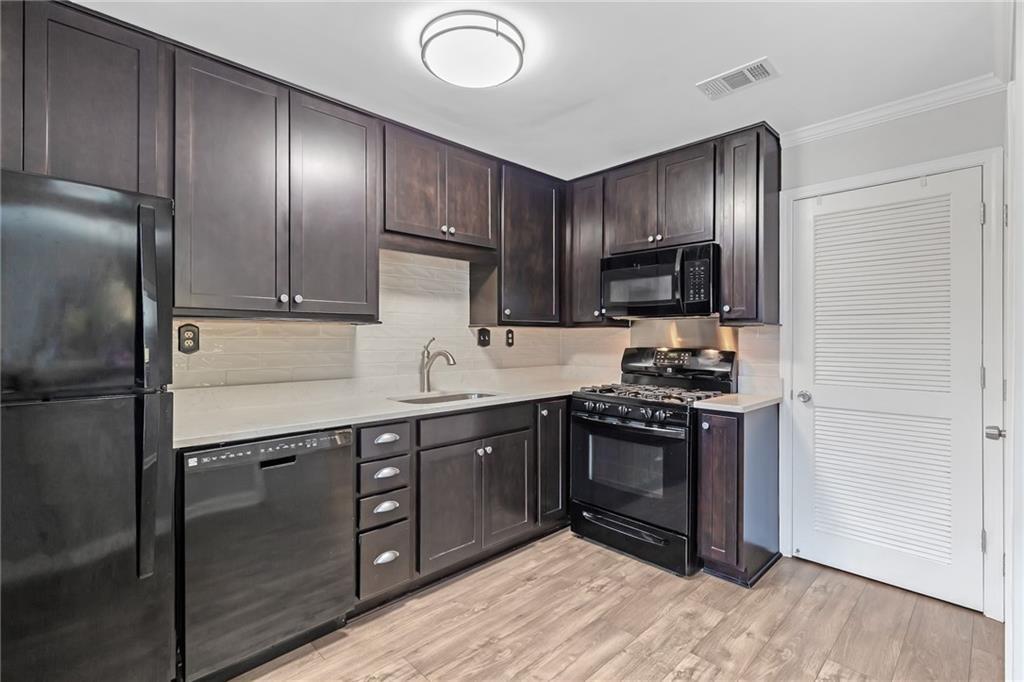 12 Surry County Place Northwest Atlanta, GA 30318 - Photo 11 of 27 a kitchen with stainless steel appliances granite countertop a stove a refrigerator and a sink with wooden floor