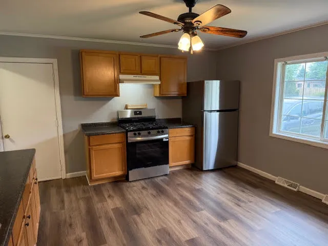 a kitchen with stainless steel appliances a stove a refrigerator a sink a microwave oven with cabinets and wooden floor