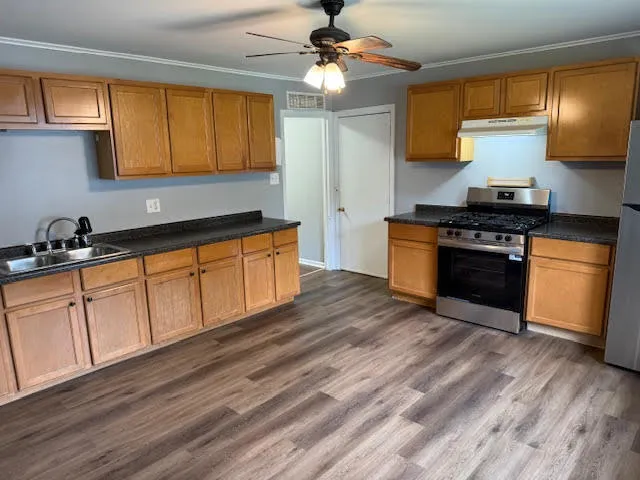 a kitchen with granite countertop wooden floors stainless steel appliances and a window