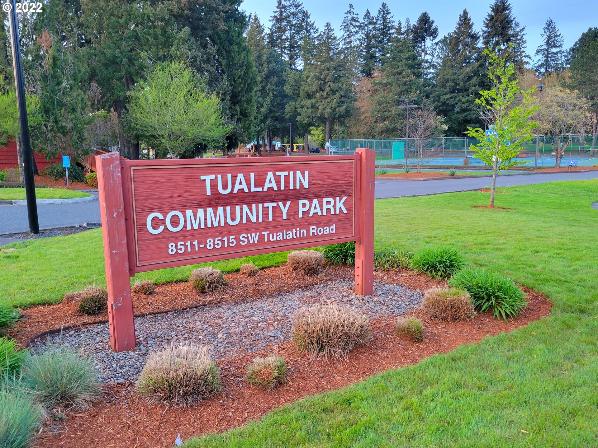 9811 Southwest Herman Road, Unit 43 Tualatin, OR 97062 - Photo 27 of 32 a sign that is sitting in the grass with trees in the background
