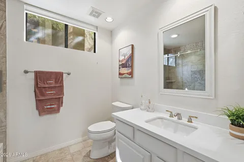 a bathroom with a granite countertop toilet sink and mirror
