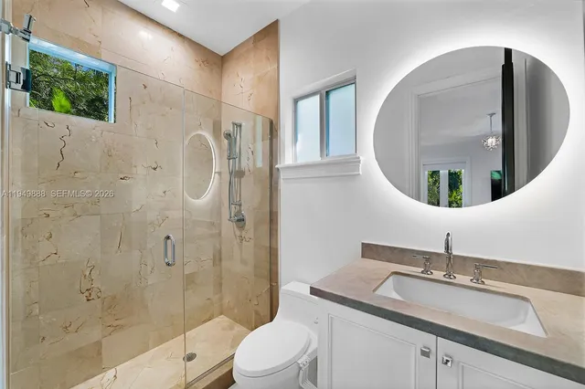 a bathroom with a granite countertop sink a toilet and shower