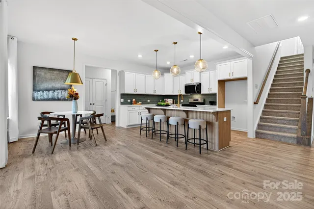 a kitchen with stainless steel appliances a dining table chairs stove and cabinets