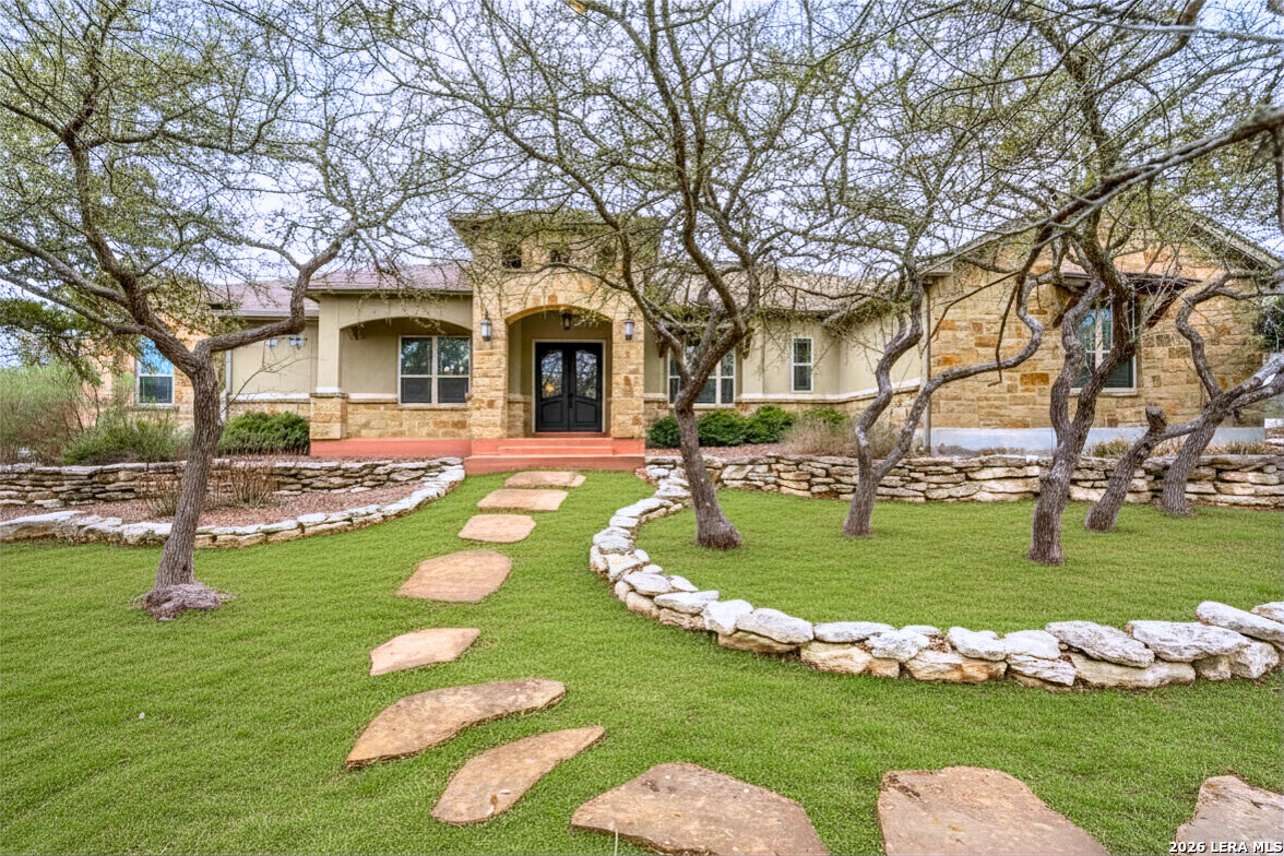 a front view of a house with garden and trees