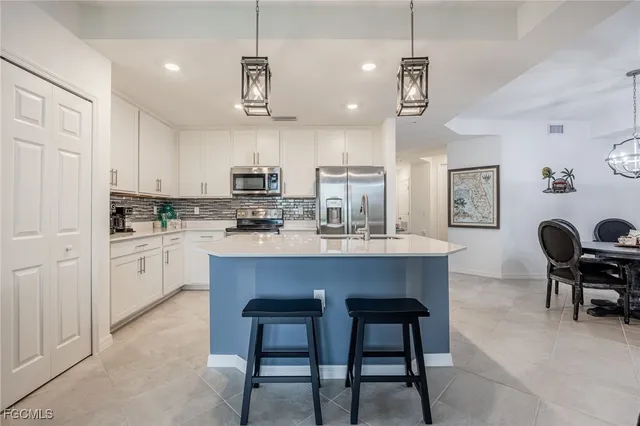 a kitchen with stainless steel appliances a table chairs refrigerator and microwave