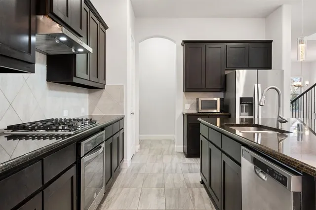 a kitchen with stainless steel appliances granite countertop a sink stove and refrigerator