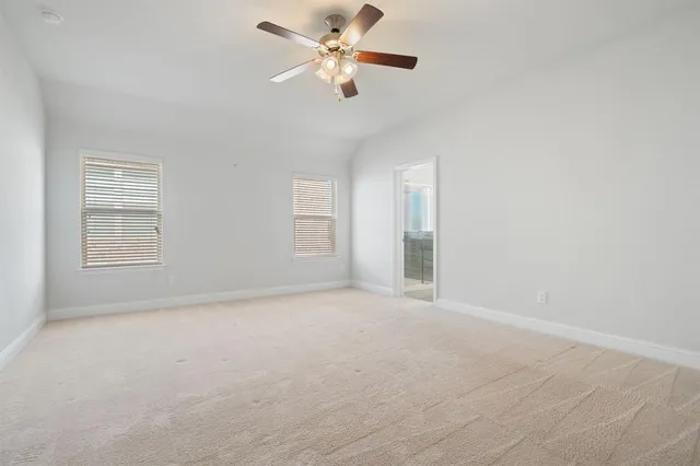 an empty room with windows and fan chandelier fan