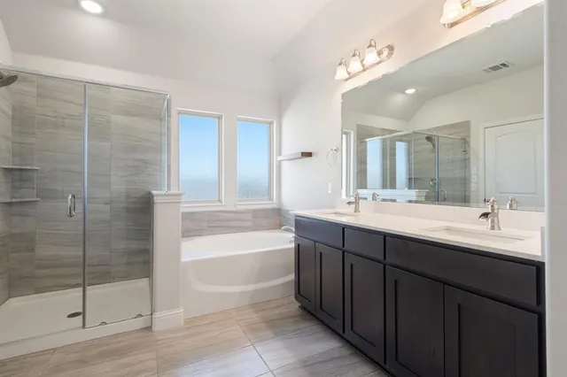 a bathroom with a double vanity sink mirror and bathtub