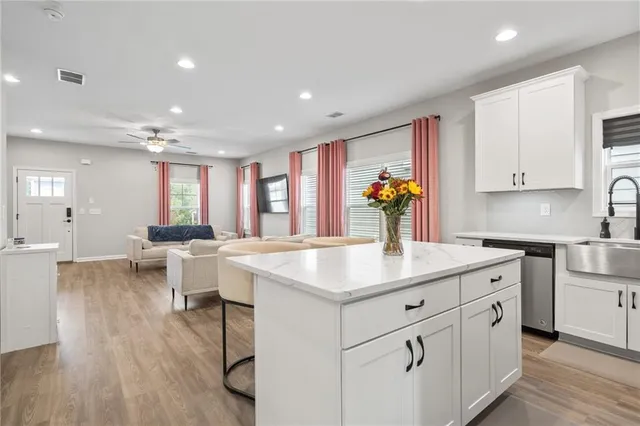 a kitchen with stainless steel appliances granite countertop a sink dishwasher and white cabinets with wooden floor