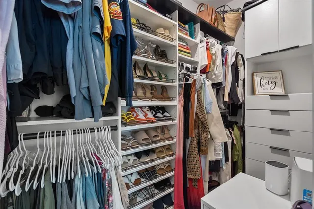 a view of walk in closet with clothes and shoes