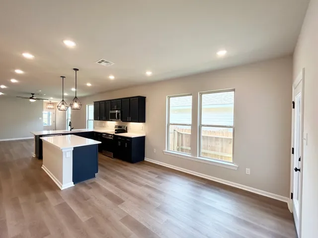 a living room with stainless steel appliances kitchen island granite countertop a large window and a couch