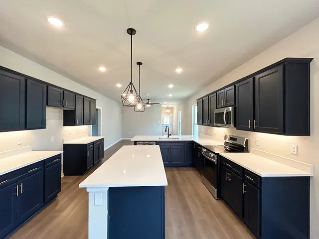 a large kitchen with a large counter top space appliances and cabinets