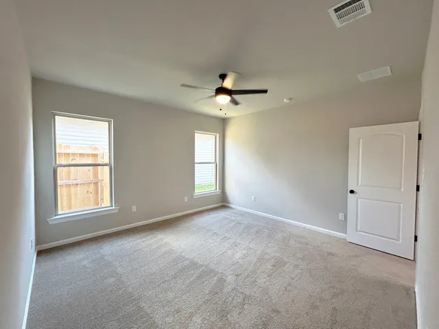 an empty room with chandelier fan and windows