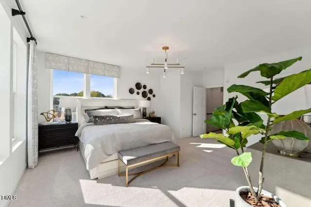 a bedroom with a bed table flowerpot and window