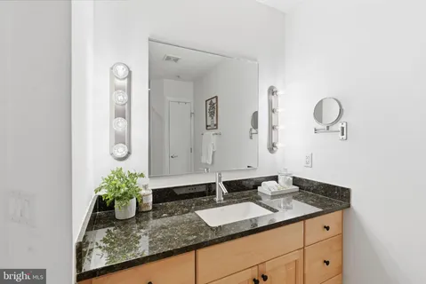 a bathroom with a granite countertop sink and a mirror