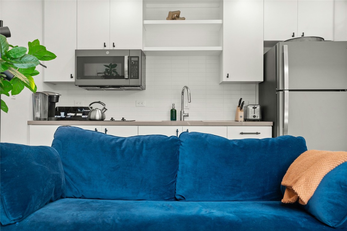 49 Navasota Street, Unit 214 Austin, TX 78702 - Photo 19 of 37 a kitchen with stainless steel appliances granite countertop a refrigerator a stove top oven a sink and dishwasher