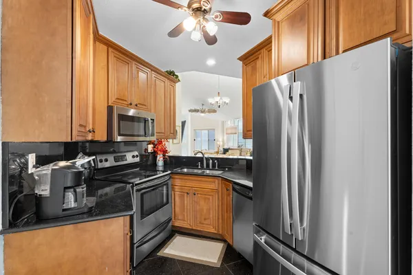 a kitchen with stainless steel appliances granite countertop a refrigerator a stove and a sink with wooden floor