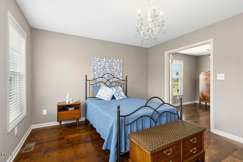 1052 Aquilla Road Benson, NC 27504 - Photo 18 of 31 a bedroom with a bed and a chandelier