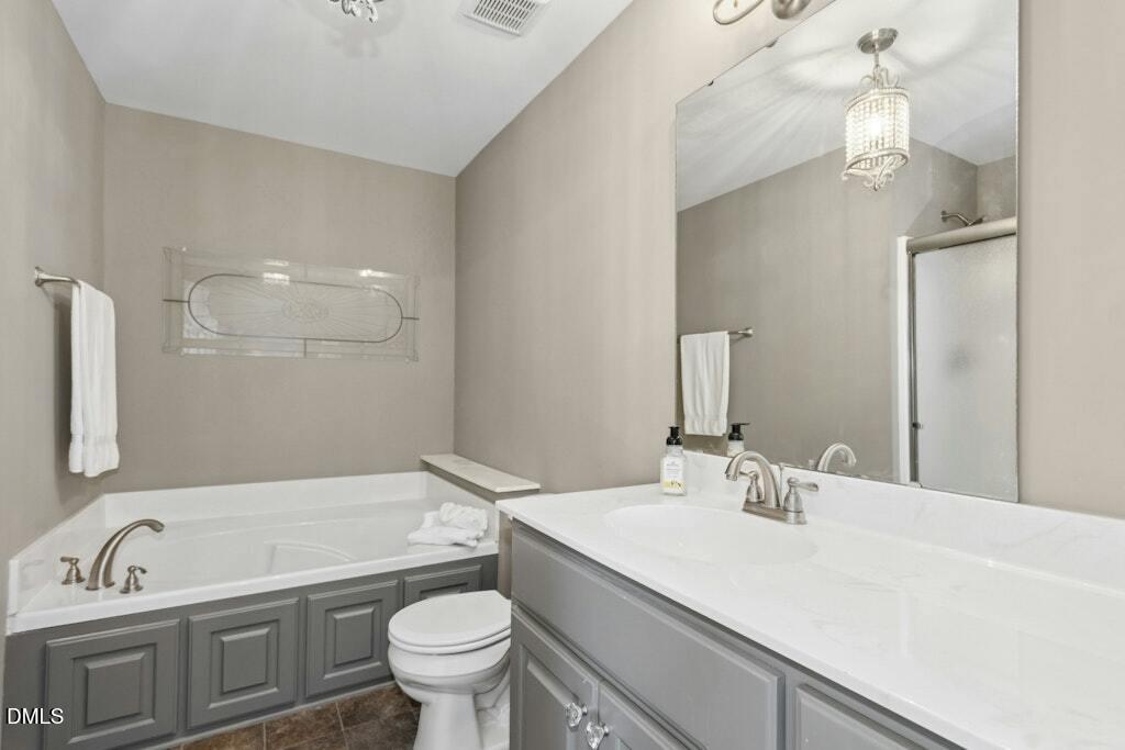 1052 Aquilla Road Benson, NC 27504 - Photo 22 of 31 a bathroom with a granite countertop sink a toilet a mirror and bathtub