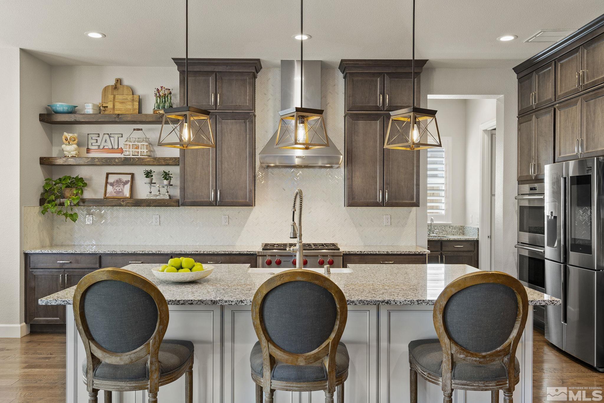 9716 Silverspar Street Reno, NV 89521 - Photo 3 of 40 a kitchen with stainless steel appliances granite countertop a dining table chairs and a refrigerator