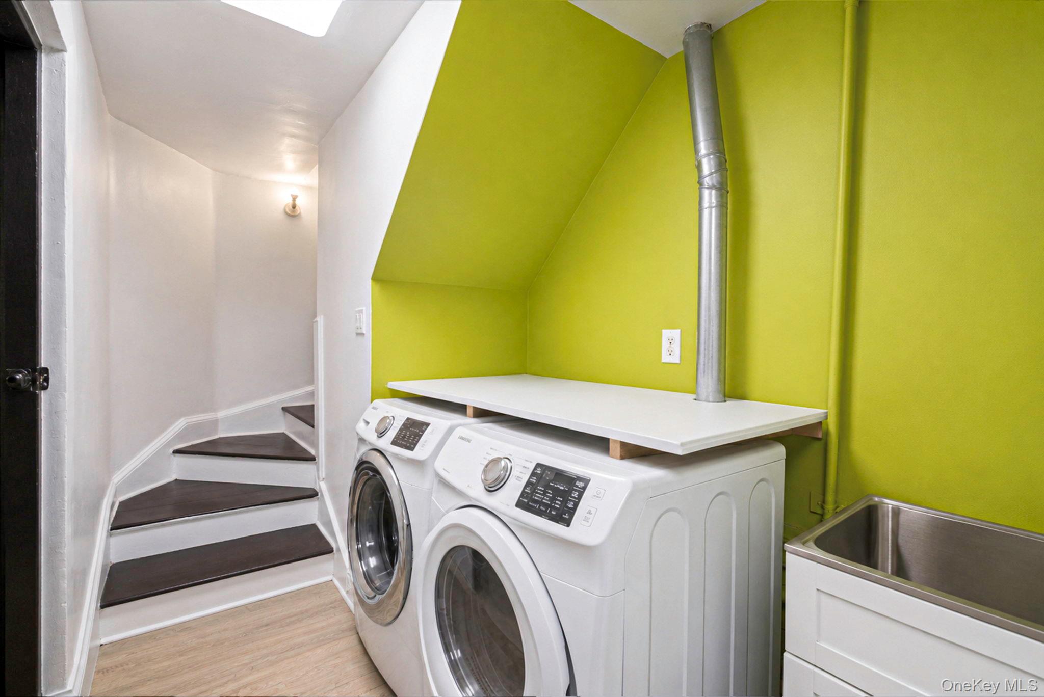 18240 Avon Road Queens, NY 11432 - Photo 26 of 30 Dedicated laundry area featuring a front-loading washer and dryer, a utility sink with a white base cabinet, a built-in countertop, and a skylight