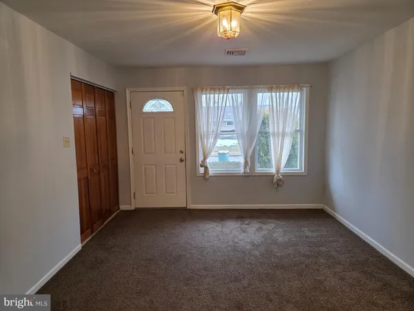an empty room with chandelier fan and windows