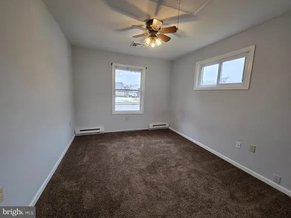 an empty room with windows and fan