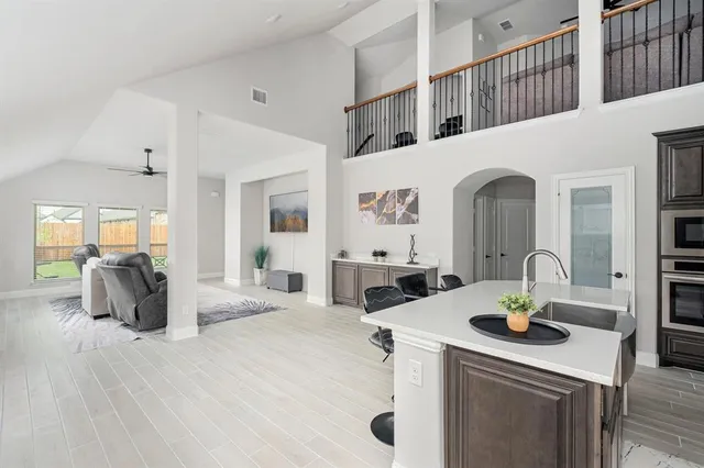 a living room with stainless steel appliances furniture a rug and a kitchen view