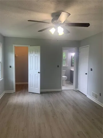 an empty room with wooden floor and way to kitchen