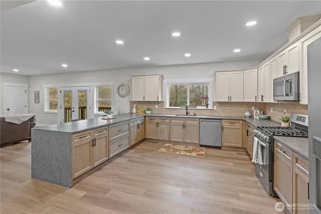 a large kitchen with stainless steel appliances granite countertop a large counter top and a stove with wooden floors