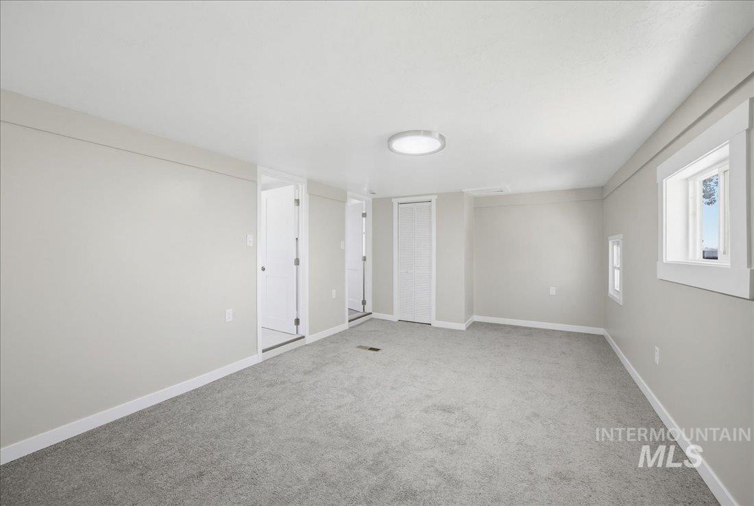 30013 Apple Valley Road Parma, ID 83660 - Photo 14 of 25 Spacious room featuring light gray walls, gray carpeting, a flush-mount ceiling light, and white trim