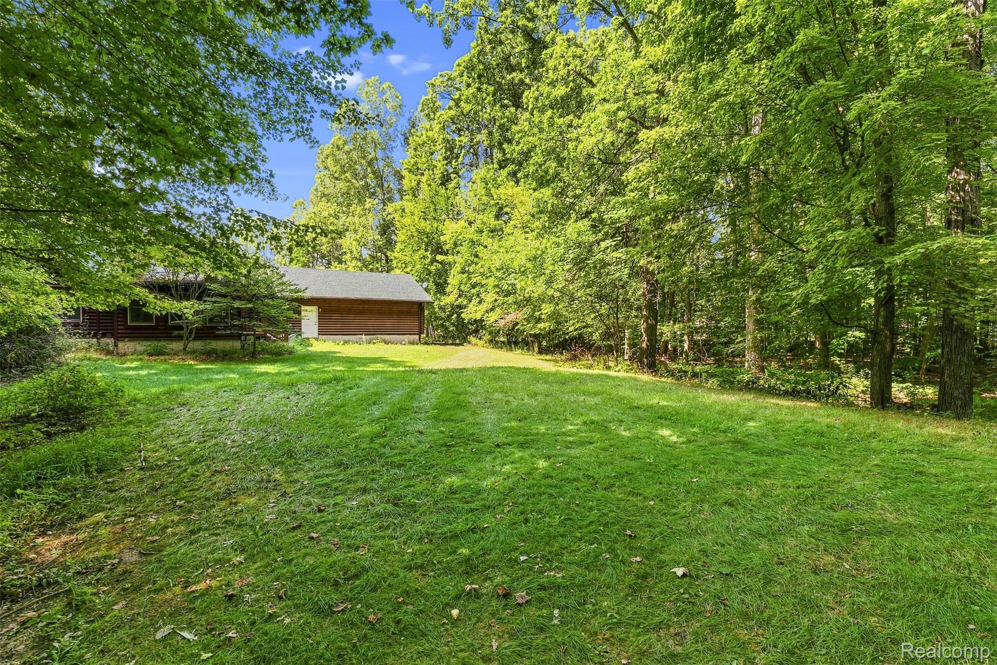 8340 North Nichols Road Flushing, MI 48433 - Photo 58 of 62 Expansive green lawn with a surrounding tree line and a wood-sided structure featuring a gabled roof