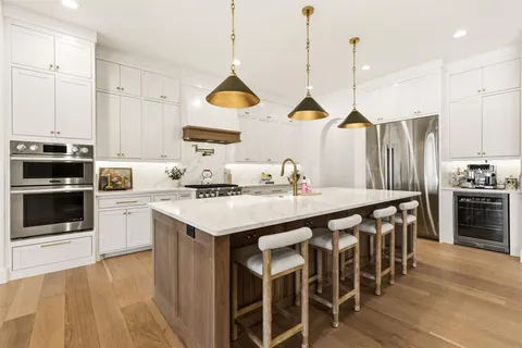 a kitchen with stainless steel appliances a stove a sink a island and chairs