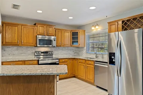 a kitchen with stainless steel appliances granite countertop a refrigerator a sink a stove a microwave and island