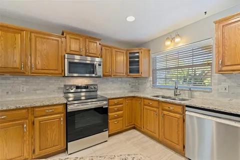 a kitchen with granite countertop cabinets stainless steel appliances a sink and window