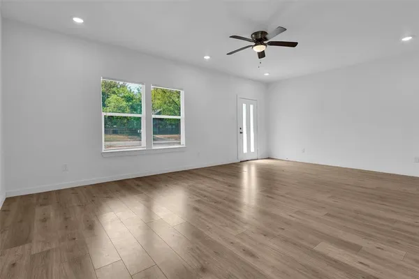 an empty room with wooden floor and windows