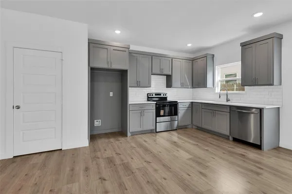 a kitchen with kitchen island granite countertop wooden floors stainless steel appliances and sink