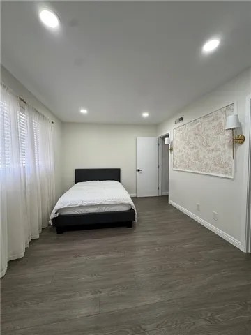 a spacious bedroom with a bed and wooden floor