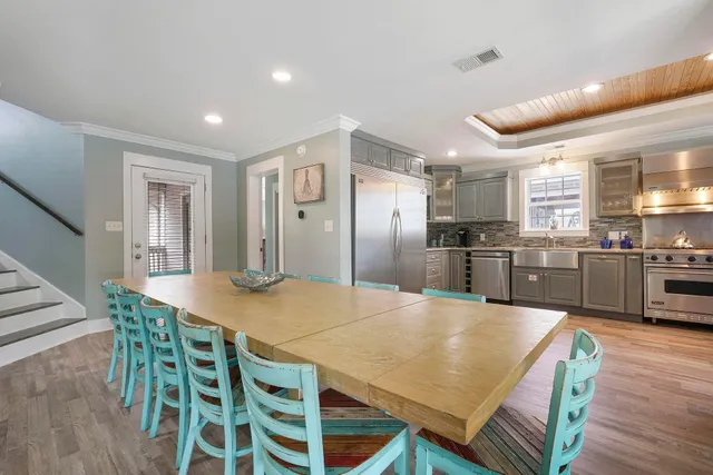 a kitchen with stainless steel appliances kitchen island granite countertop a refrigerator a stove a sink a dining table and chairs with wooden floor