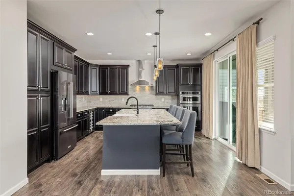 a kitchen with kitchen island stainless steel appliances a sink a stove a refrigerator cabinets and wooden floor