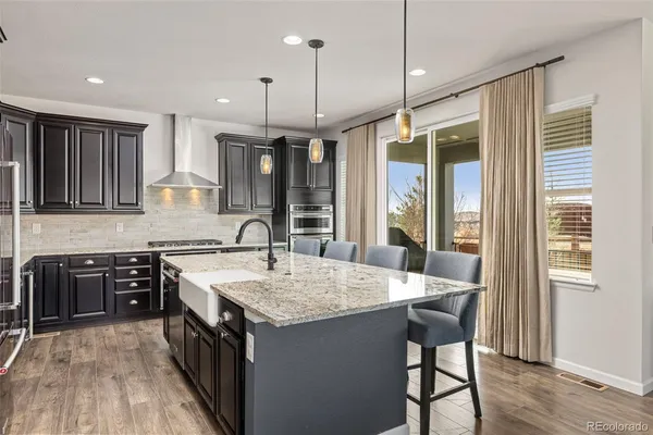 a kitchen with a stove a sink a kitchen island with wooden cabinets and wooden floor